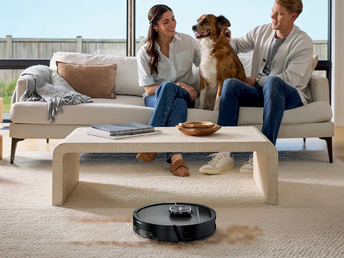 The robot cleaning pet hair from a rug beside a sleeping dog